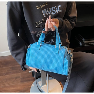 Dettaglio della borsa a tracolla a scacchi blu con tessuto testurizzato e tasche laterali