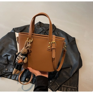 Detailed texture of brown pebble leather tote bag with cute rabbit charm and gold hardware