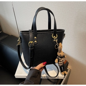 Detail of black lychee grain leather tote bag with gold hardware and rabbit pendant