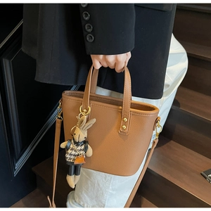 Brown lychee leather bucket bag with gold hardware and a cute rabbit charm detail