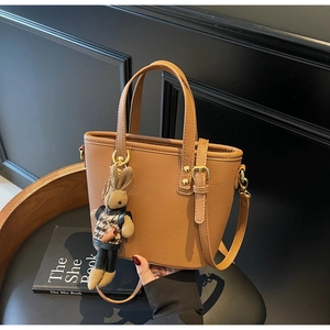 Brown litchi grain bucket bag with a cute rabbit charm and golden hardware detail
