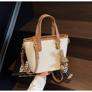Detail of cream bucket bag with litchi texture, brown trim and cute rabbit charm
