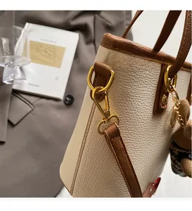 Detail of contrast leather bucket bag with gold hardware and a cute bear charm
