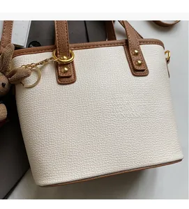 Close-up of litchi grain leather tote bag with brown handles and a cute rabbit charm