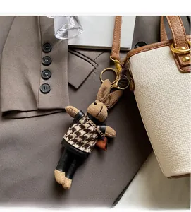 Detail of cute rabbit charm with houndstick vest hanging on a beige bucket bag