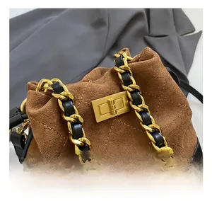 Détail du fermoir doré rotatif et de la bandoulière en chaîne de ce sac seau marron