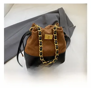 Détail du sac seau rétro en daim marron et cuir matelassé noir avec fermoir doré brillant