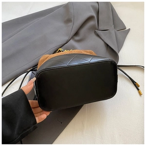 Détail du sac seau contrasté en cuir matelassé noir et daim marron avec cordon de serrage