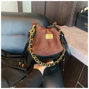 Détail du sac seau vintage en daim marron, cuir noir et poignée en chaîne dorée