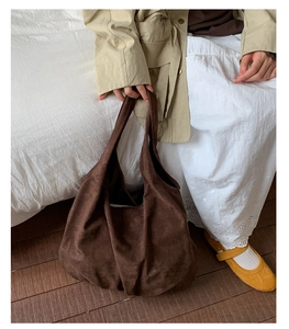 Close-up of a large dark brown suede dumpling bag with soft texture and slouchy design