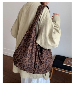 Detailed side view of large leopard print tote bag with wide strap on a female model