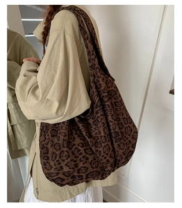 Close-up of a large leopard print tote bag styled with a beige trench coat for a casual look