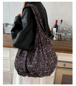 Detail of dark grey leopard print tote bag with soft suede texture shown on model