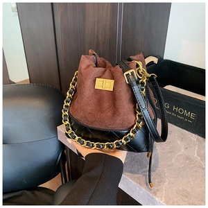 Détail du sac seau vintage en daim marron et cuir noir avec bandoulière chaîne dorée