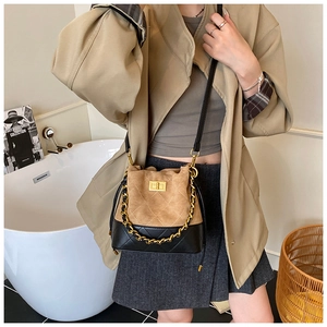 Détail du sac seau bicolore en daim kaki et cuir noir avec chaîne dorée chic