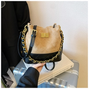 Détail du sac seau matelassé en daim camel et cuir noir avec finitions dorées