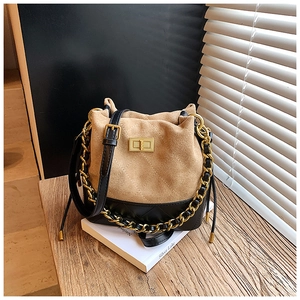 Détail du sac seau bicolore avec fermoir doré et surpiqûres sur un support blanc