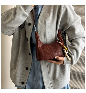 Close-up of brown woven leather hobo bag with colorful wooden bead tassel charm detail