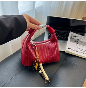 Detailed view of red woven handbag with silver metal buckle and colorful bead charm