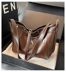 Detail of dark brown vintage leather shoulder bag with white stitching in a gift box