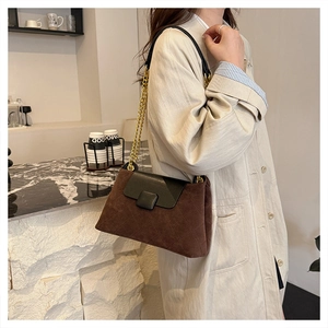 Detail of dark brown quilted shoulder bag with gold chain strap on model in beige coat