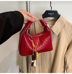 Detailed view of red woven leather hobo bag with unique colorful wooden bead charm