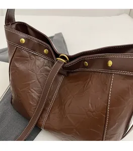 Detail of dark brown tote bag featuring retro crumpled texture and white contrast stitching
