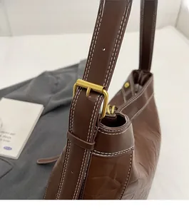 Close-up of brown PU leather tote bag with white contrast stitching and gold metal buckle