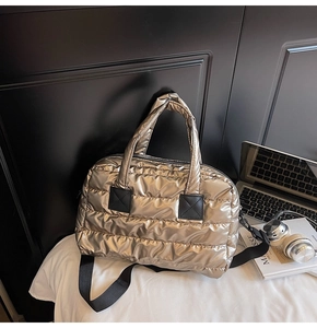 Detail of metallic champagne tote bag with horizontal quilting and black shoulder strap
