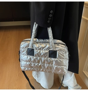 Detail view of silver puffer tote bag with quilted metallic finish and black straps