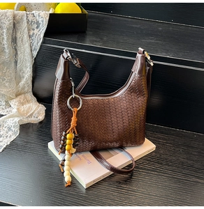 Detail of dark brown woven leather hobo bag with silver zipper and beaded tassel charm