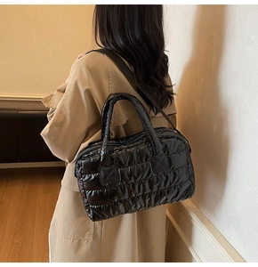 Puffy black quilted tote bag with glossy finish shown on model in khaki trench coat