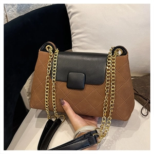 Detail view of brown suede and black leather patchwork bag with gold chain strap