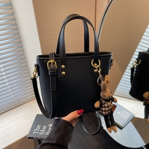 Minimalist black tote handbag with gold hardware and a cute bunny charm on display