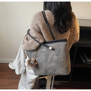 Detail of grey textured tote bag with detachable brown fuzzy monster charm decoration