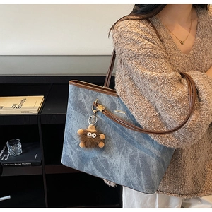 Detailed close-up of blue marble denim tote bag with leather trim and plush charm