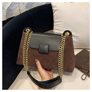 Detail of brown quilted suede shoulder bag with gold chain strap and black leather flap