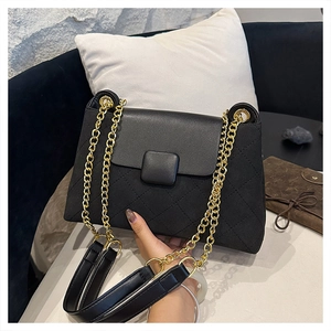 Detail of black quilted leather shoulder bag with gold chain strap and square metal buckle
