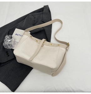 Detail of cream white leather shoulder bag featuring vintage gold rivets and wrinkled texture