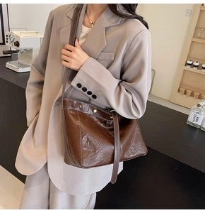 Detail of vintage brown leather tote bag with contrast stitching and adjustable metal buckle