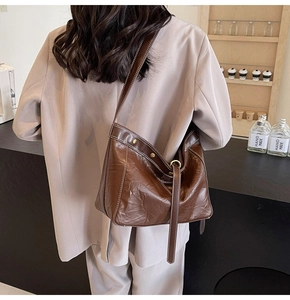 Detail view of large brown hobo bag featuring contrast white stitching and gold hardware