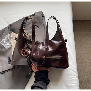 Détail d'un sac cabas en cuir marron foncé poli avec zip avant et charme de nœud décoratif