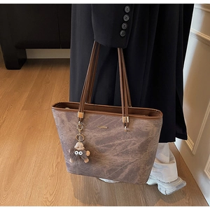Detail of large brown tote bag with marble texture and a grey furry monster charm