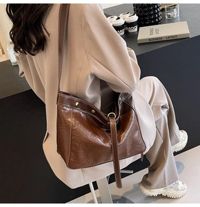 Detail of vintage brown leather handbag with contrast stitching and metallic rivets