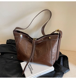Detailed macro view of retro brown pleated leather tote with adjustable gold buckles
