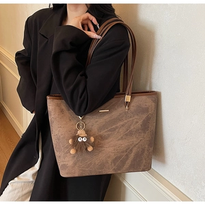 Detail view of large tote bag in marbled brown leather with chic monster plush charm