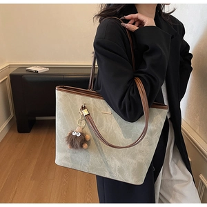 Detail showing marble texture on tote bag with brown leather strap and plush doll charm