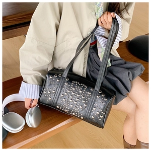 Close-up of black bucket bag with silver metal studs and punk style shoulder straps
