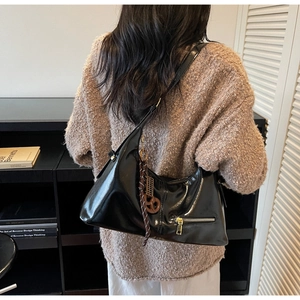 Détail du sac hobo en cuir brillant noir avec fermeture éclair dorée et pendentif