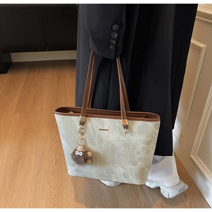 Detail of green marble texture tote bag with brown handles and a plush doll pendant